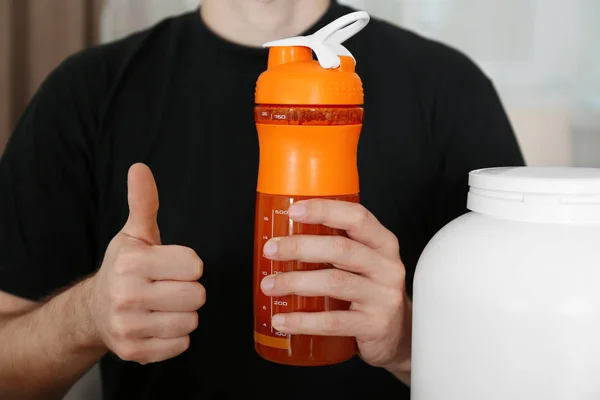 Man holding bottle with protein shake indoors