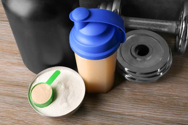 Sammansättning med proteinshake, pulver och hantel på bord — Stockfoto