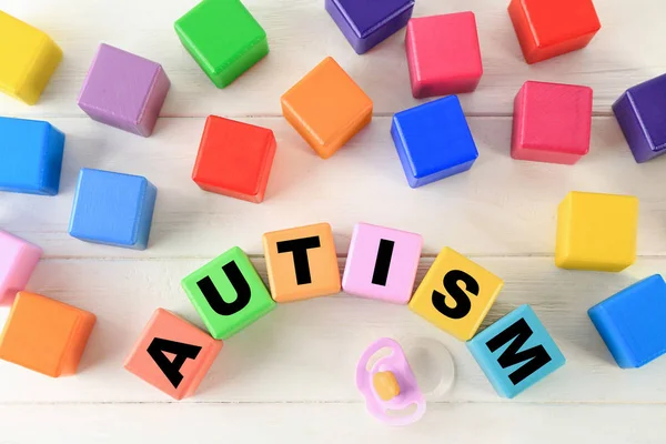 Color cubes with word AUTISM on wooden background