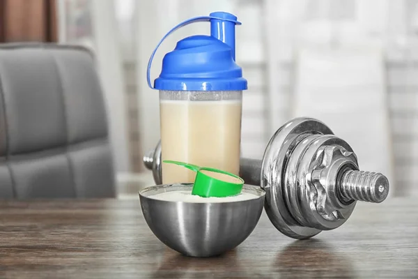 Flasche mit Proteinshake, Pulver und Hantel auf dem Tisch — Stockfoto