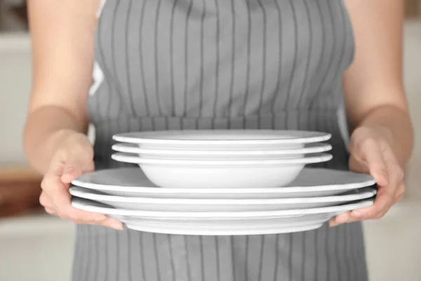 Женщина держит стопку тарелок, крупным планом — стоковое фото
