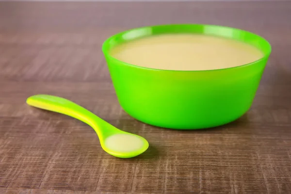 Colher e tigela com mingau de cereal bebê na mesa de madeira — Fotografia de Stock