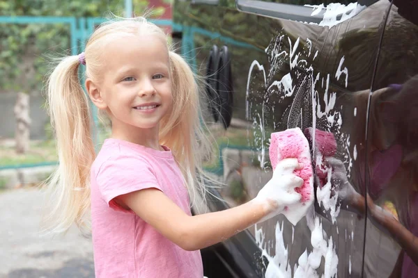 Adorable niña lavando coche con esponja al aire libre — Foto de Stock