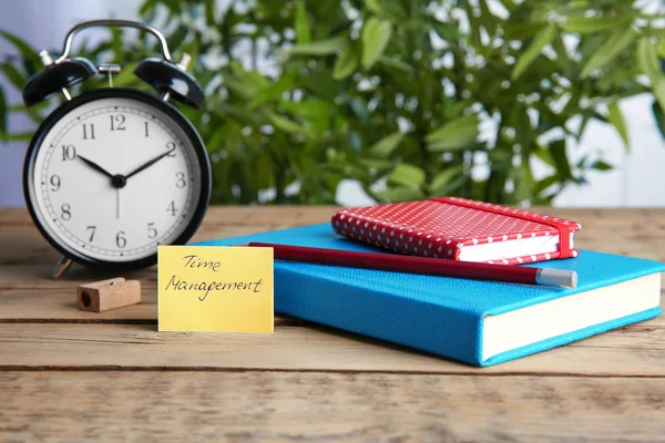 Time management concept. Composition with alarm clock on wooden table