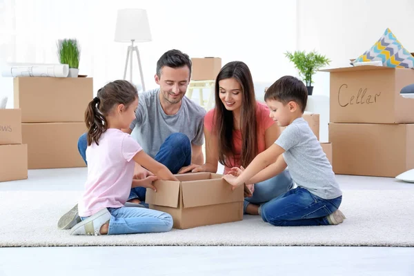 Familia feliz desempacar cajas móviles en la habitación en el nuevo hogar — Foto de Stock