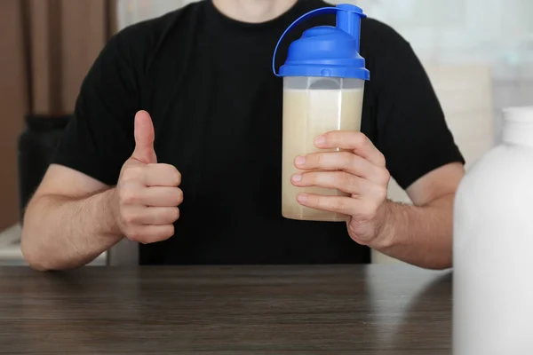 Man holding bottle with protein shake at table — Stock Photo, Image