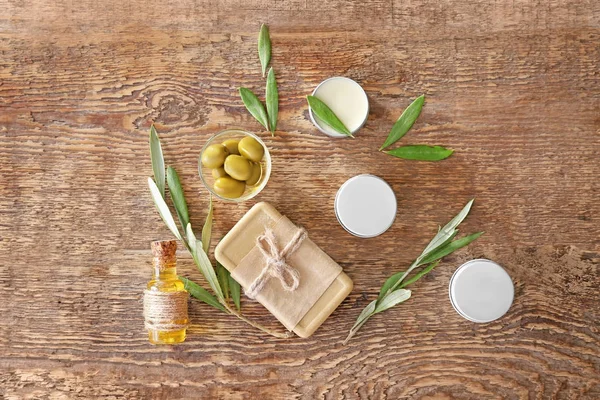 Pots à la crème et savon à l'extrait d'olive sur fond de bois — Photo