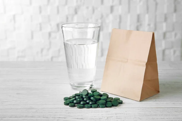 Таблетки спирулина и стакан воды — стоковое фото