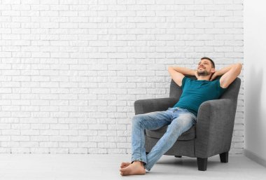 Genç adam tuğla duvar arka koltuk dinlenme