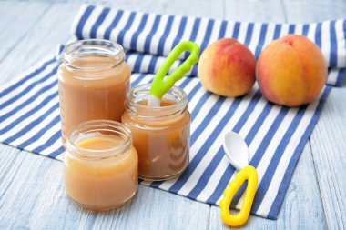 Ahşap masa üzerinde farklı bebek maması ile kavanoz