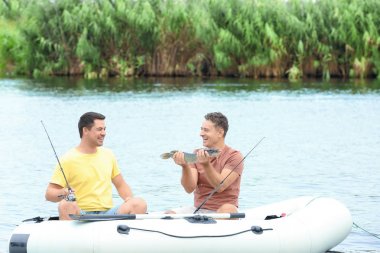 Riverside'da şişme botla taze yakalanmış balık ile iki adam