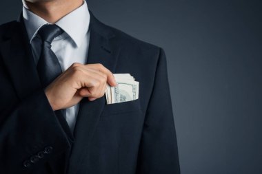 Koyu arka plan üzerinde cebinde para olan adam