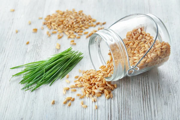 Jar met zaden en tarwe gras op houten tafel — Stockfoto