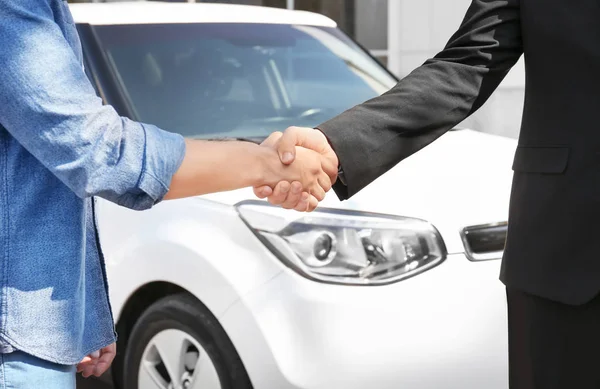 Pelanggan dan salesman berjabat tangan dekat mobil baru di luar ruangan — Stok Foto