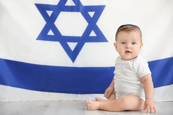 Lindo bebé en kippah sentado en el suelo contra la gran bandera de Israel — Foto de Stock