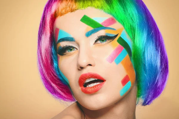 Giovane donna con trucco creativo e capelli arcobaleno su sfondo di colore — Foto Stock