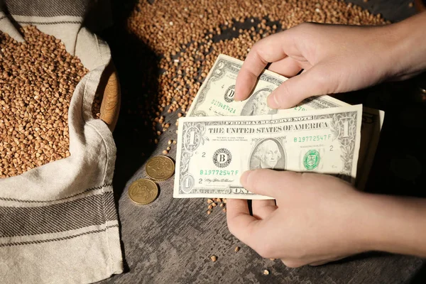 Woman counting money near raw buckwheat — Stock Photo, Image