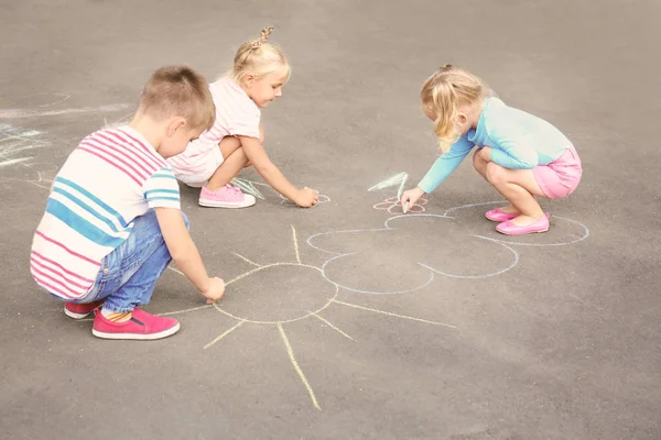 Leuke lieve kinderen tekenen met krijtjes op asfalt buitenshuis — Stockfoto