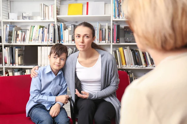 Jonge moeder en kleine jongen over de bijeenkomst met de leraar op school — Stockfoto