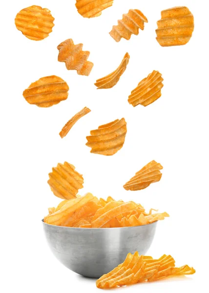 Tasty potato chips falling into bowl — Stock Photo, Image