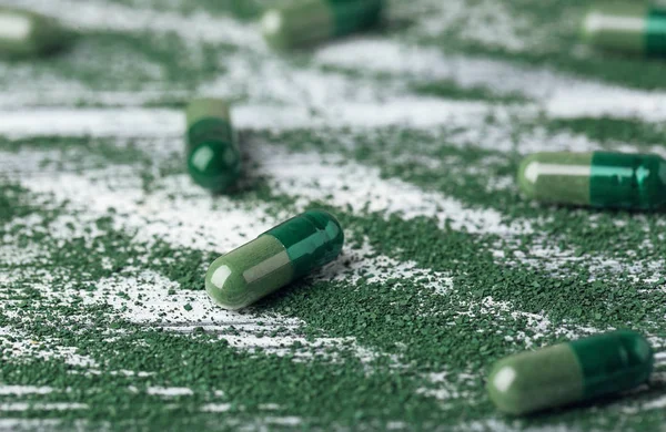 Spirulina cápsulas com pó na mesa — Fotografia de Stock