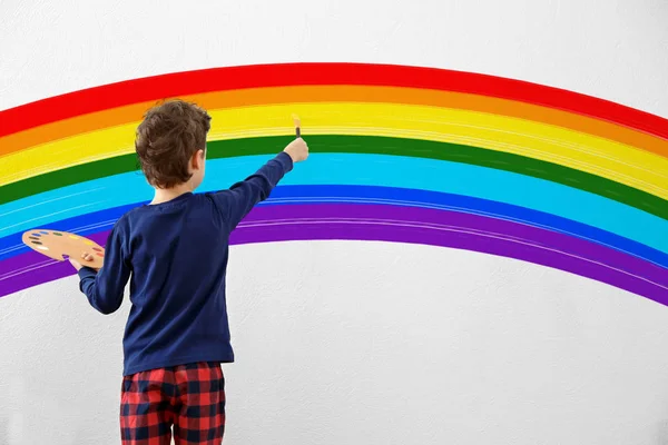 Χαριτωμένο μικρό αγόρι rainbow ζωγραφική στον τοίχο στο δωμάτιο — Φωτογραφία Αρχείου