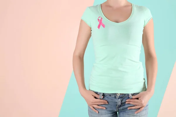 Mujer joven con cinta rosa sobre fondo de color. Concepto de cáncer de mama —  Fotos de Stock