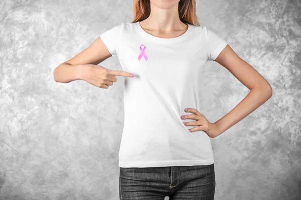 Young woman with pink ribbon on color background. Breast cancer concept — Stock Photo, Image