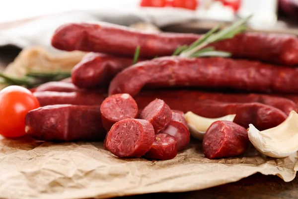 Delicious smoked sausages on parchment — Stock Photo, Image