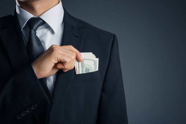 Man with money in pocket on dark background