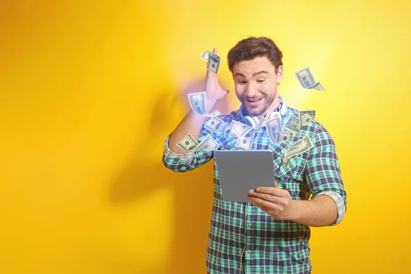 Dinheiro voando para fora do tablet, enquanto o homem usá-lo no fundo amarelo — Fotografia de Stock