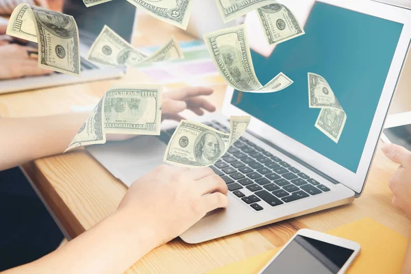 Dinero volando fuera de la computadora portátil mientras el hombre lo usa en la mesa en la oficina — Foto de Stock