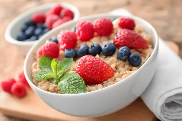 Leckere Haferflocken mit Beeren in Schüssel auf dem Tisch — Stockfoto