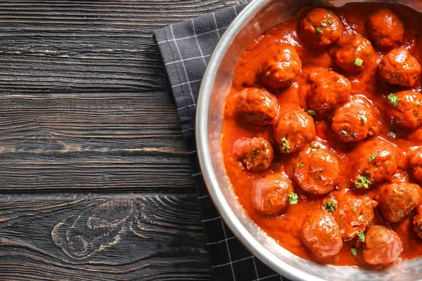 Кастрюля с вкусными фрикадельками в томатном соусе на столе — стоковое фото