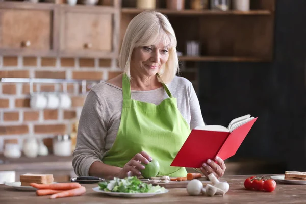 Mature woman cooking in kitchen — Stock Photo, Image