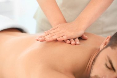 Genç adam spa salonunda masaj yaptırıyor.