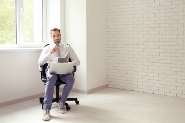 Tekli pencere ofisinde yakınındaki otururken dizüstü bilgisayar ile genç adam