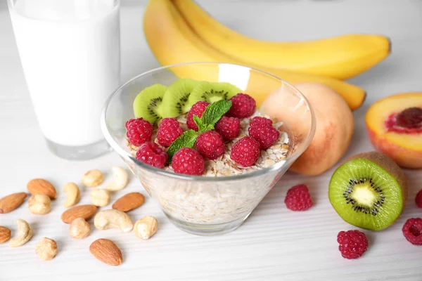 Ciotola di farina d'avena con lamponi e kiwi in tavola — Foto Stock