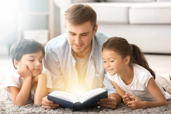 Padre e figli che leggono libro a casa — Foto Stock