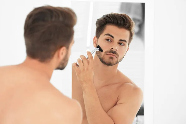 Schöner junger Mann rasiert sich im Badezimmer — Stockfoto