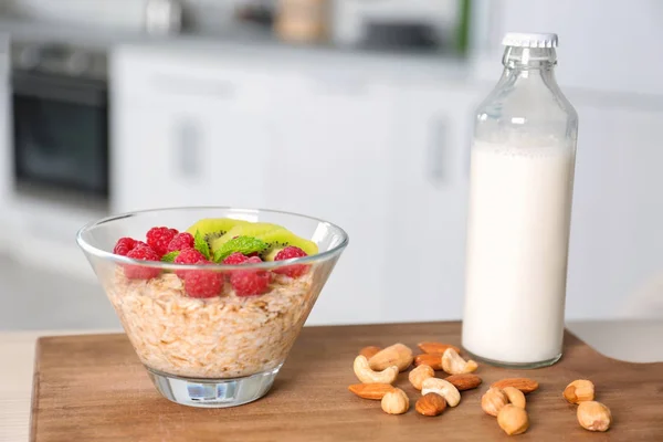 Bowl of oatmeal and bottle of milk on wooden board — Stock Photo, Image