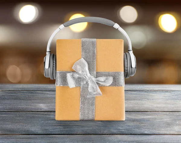 Christmas music concept. Gift box with headphones on blurred background