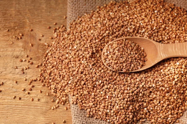 Raw buckwheat and wooden spoon — Stock Photo, Image