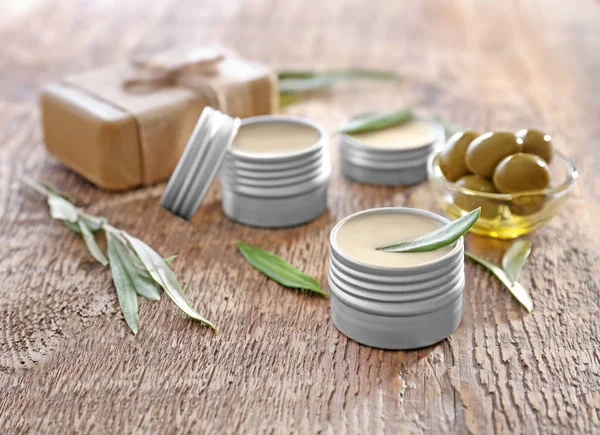 Jars with cream with olive extract on wooden background — Stock Photo, Image