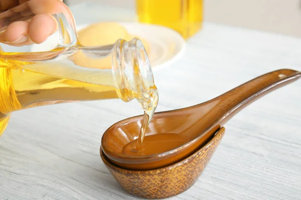 Pouring oil into spoon on wooden table — Stock Photo, Image