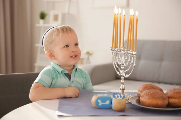 Leuke jongen zitten in de buurt van negen-vertakt menora op tafel thuis — Stockfoto