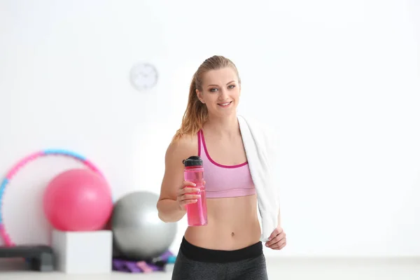 Sportovní mladá žena s lahví vody v tělocvičně — Stock fotografie