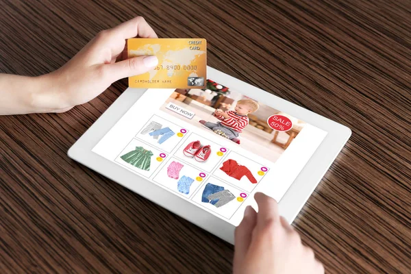 Vrouw met behulp van Tablet PC- en creditcard voor online winkelen van internet aan tafel — Stockfoto