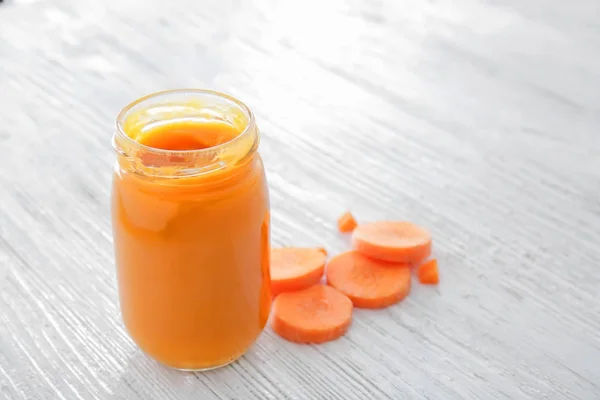 Pot avec de savoureux aliments pour bébés sur une table en bois — Photo