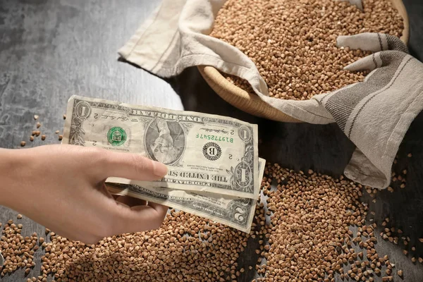 Mujer sosteniendo dinero cerca de trigo sarraceno crudo —  Fotos de Stock